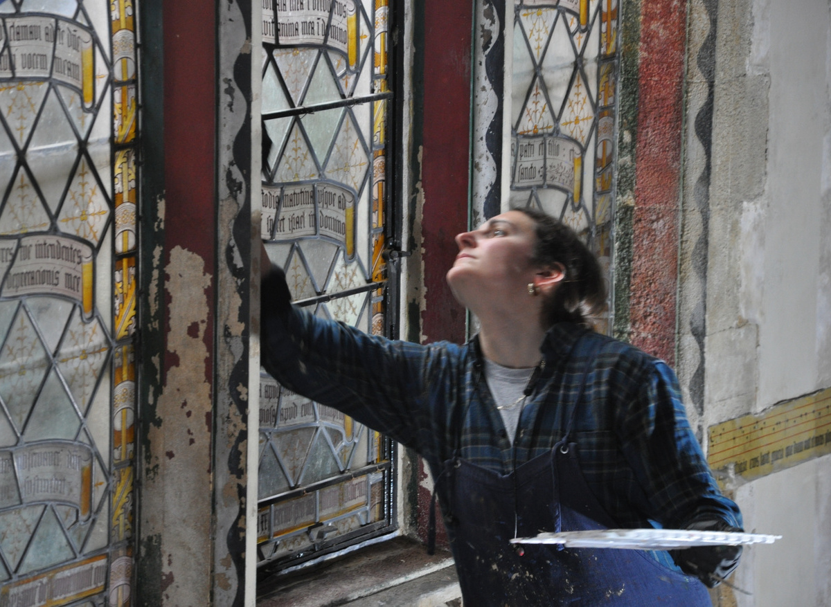 Conservator Rosie Bright retouching the tracery window in bay 3 