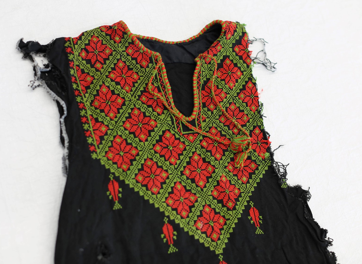 Detail of the embroidered chest panel of the young woman’s dress, with sleeves torn off and lost 