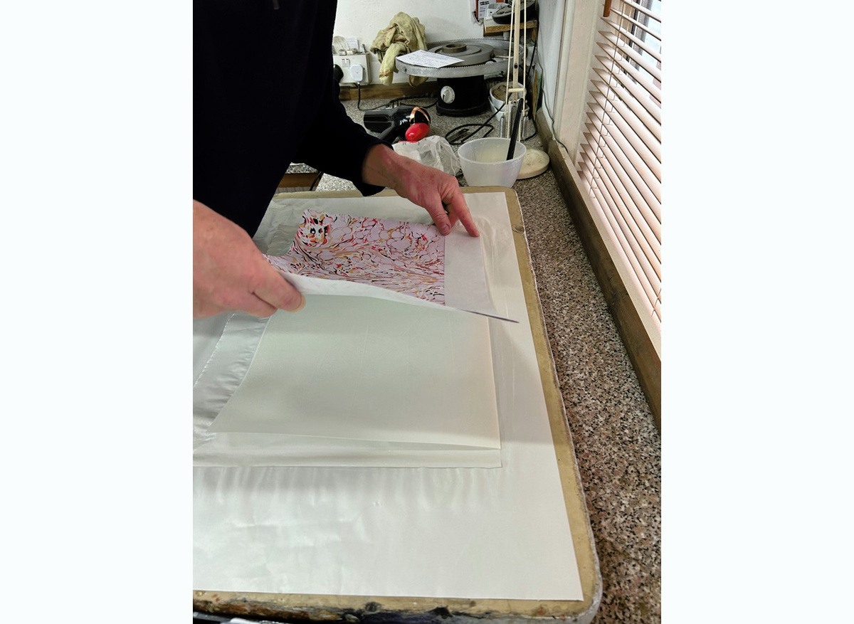 Laying down the marbled paper onto the glued vellum