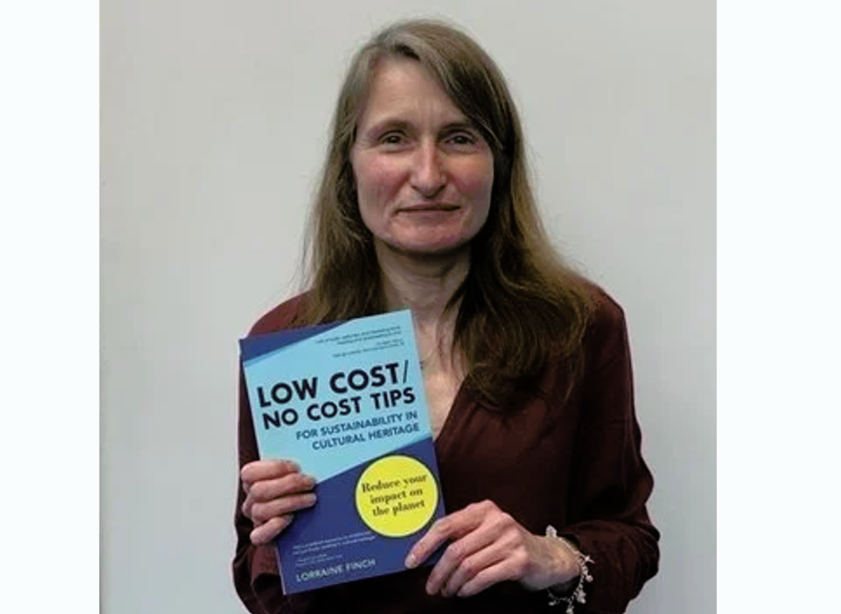 Lorraine Finch holding her book, Low cost/no cost tips for sustainability in cultural heritage