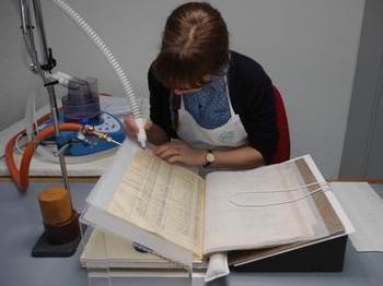 Emma Nichols applying adhesive vapour to a leaf of the nominal roll