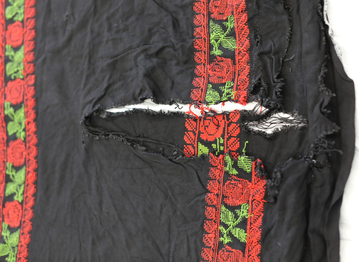 Detail of the embroidered chest panel of the young woman’s dress, with sleeves torn off and lost